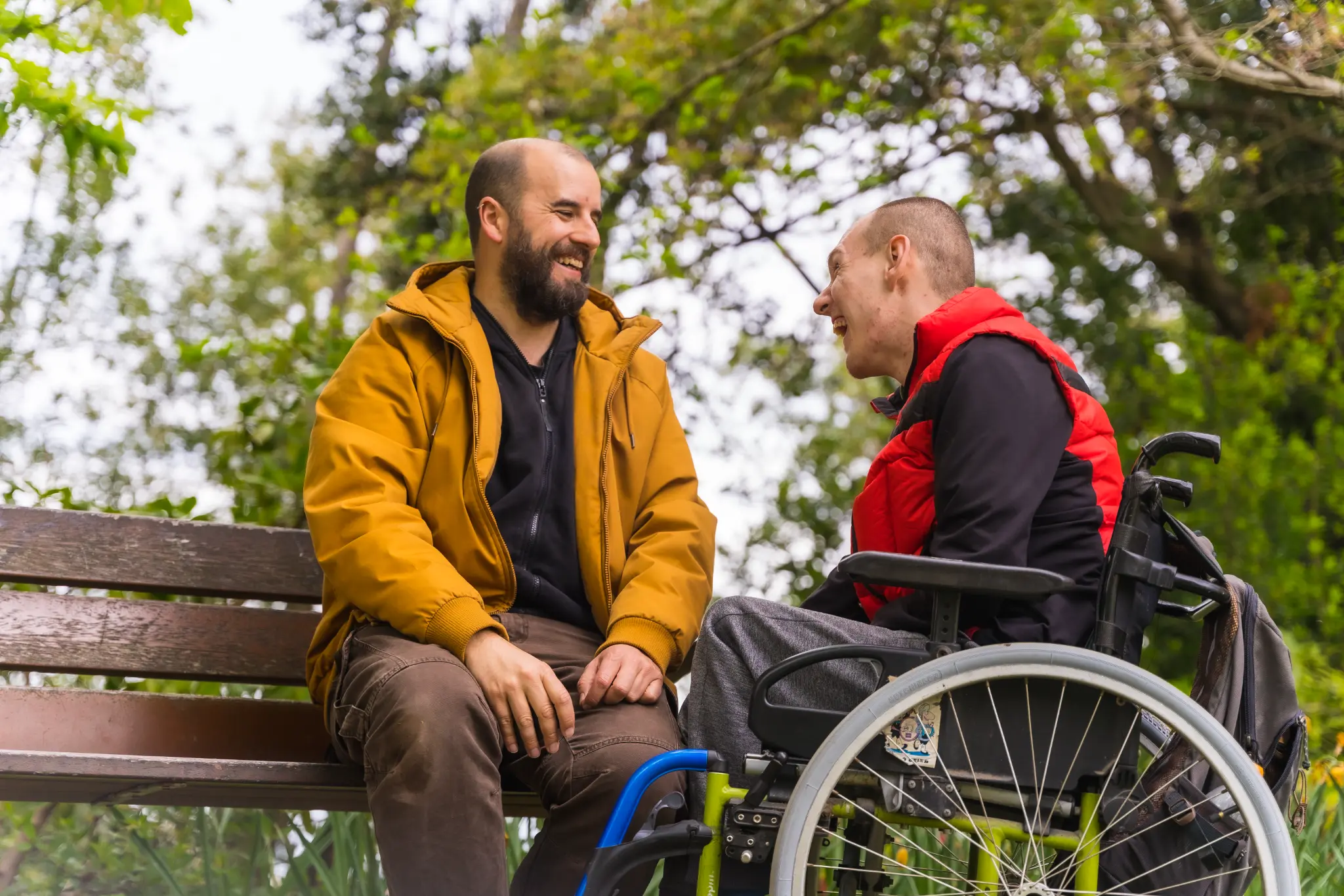 Two friends laughing together, one in a wheelchair
