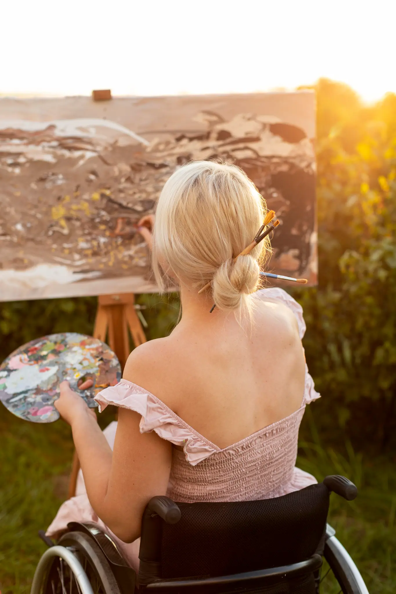 Woman in wheelchair painting outdoors